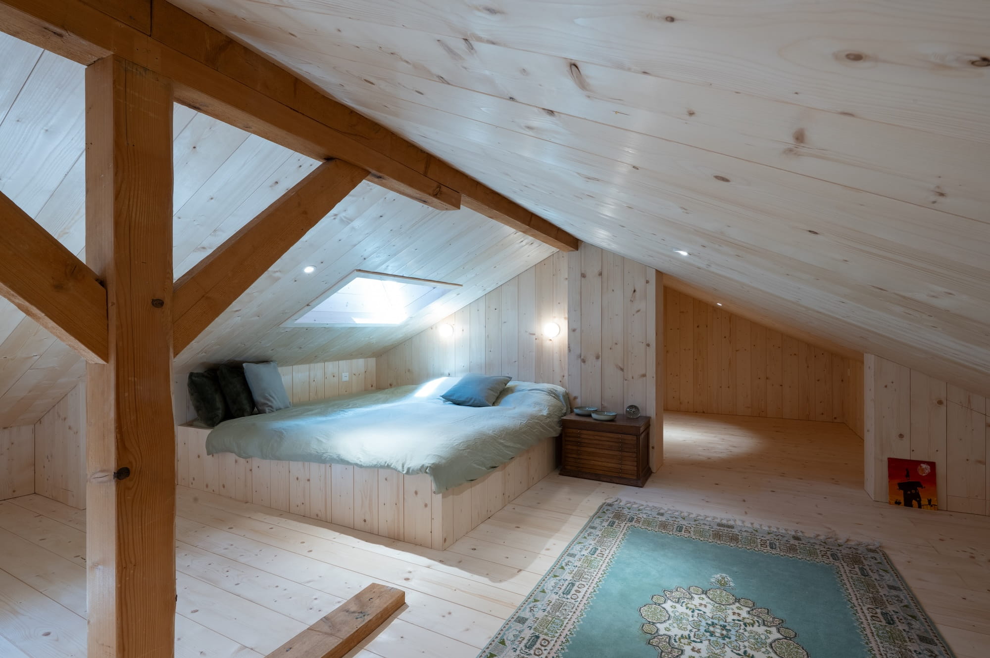 Espace chambre d'amis chaleureux et cosy sous les pentes en bois de sapin.